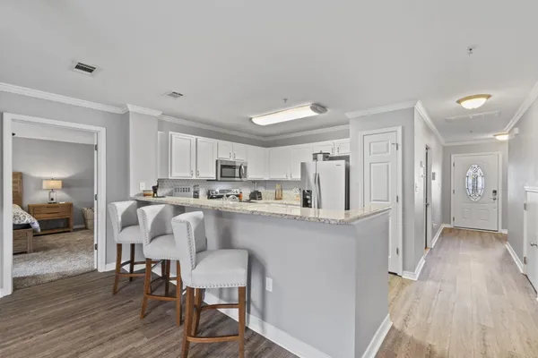 a living room with stainless steel appliances furniture and wooden floor