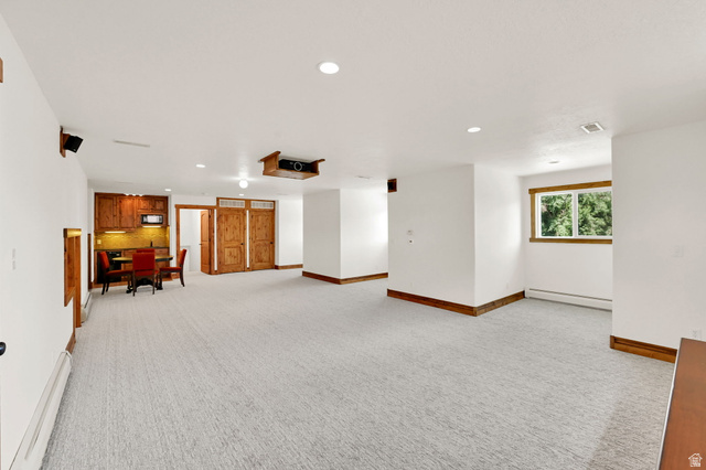 13658 South Fort Street Draper, UT 84020 - Photo 34 of 87 Spacious lower level featuring light gray textured carpeting, recessed lighting, a built-in wet bar with wood cabinetry and a microwave, wood-paneled doors, and a window with wood trim