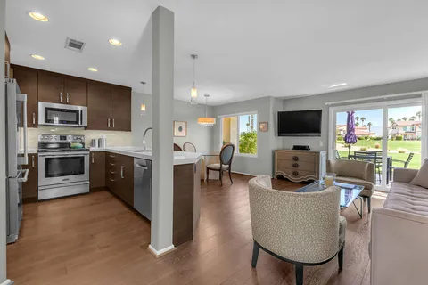 a kitchen with stainless steel appliances kitchen island granite countertop a stove a sink a microwave a dining table and chairs