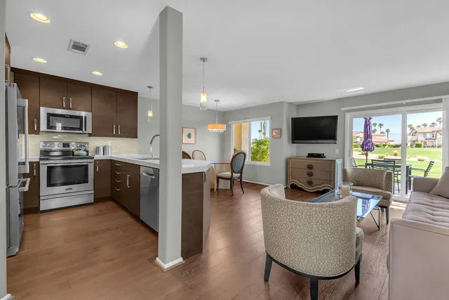 a kitchen with stainless steel appliances kitchen island granite countertop a stove a sink a microwave a dining table and chairs