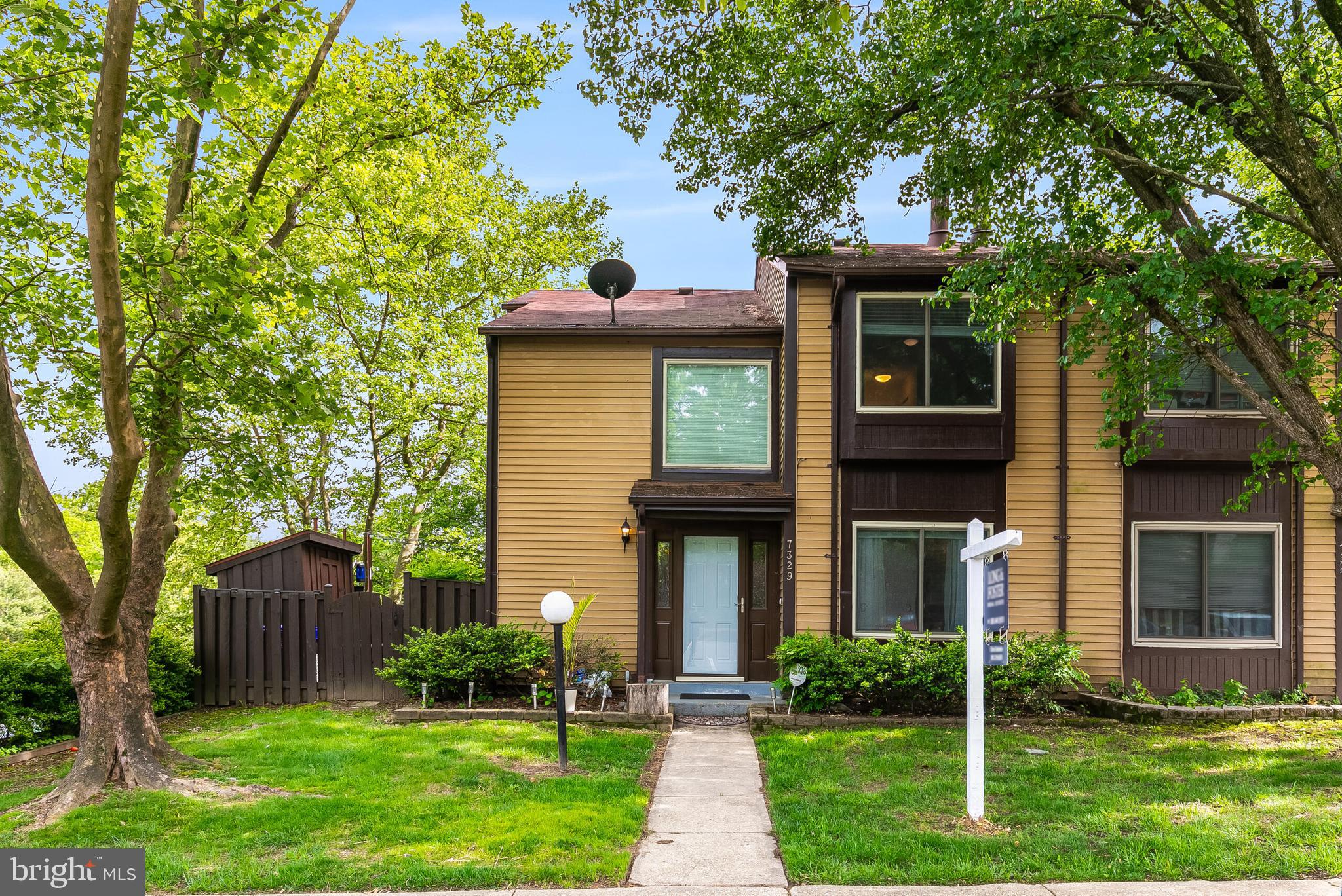 a front view of a house with a yard and large trees