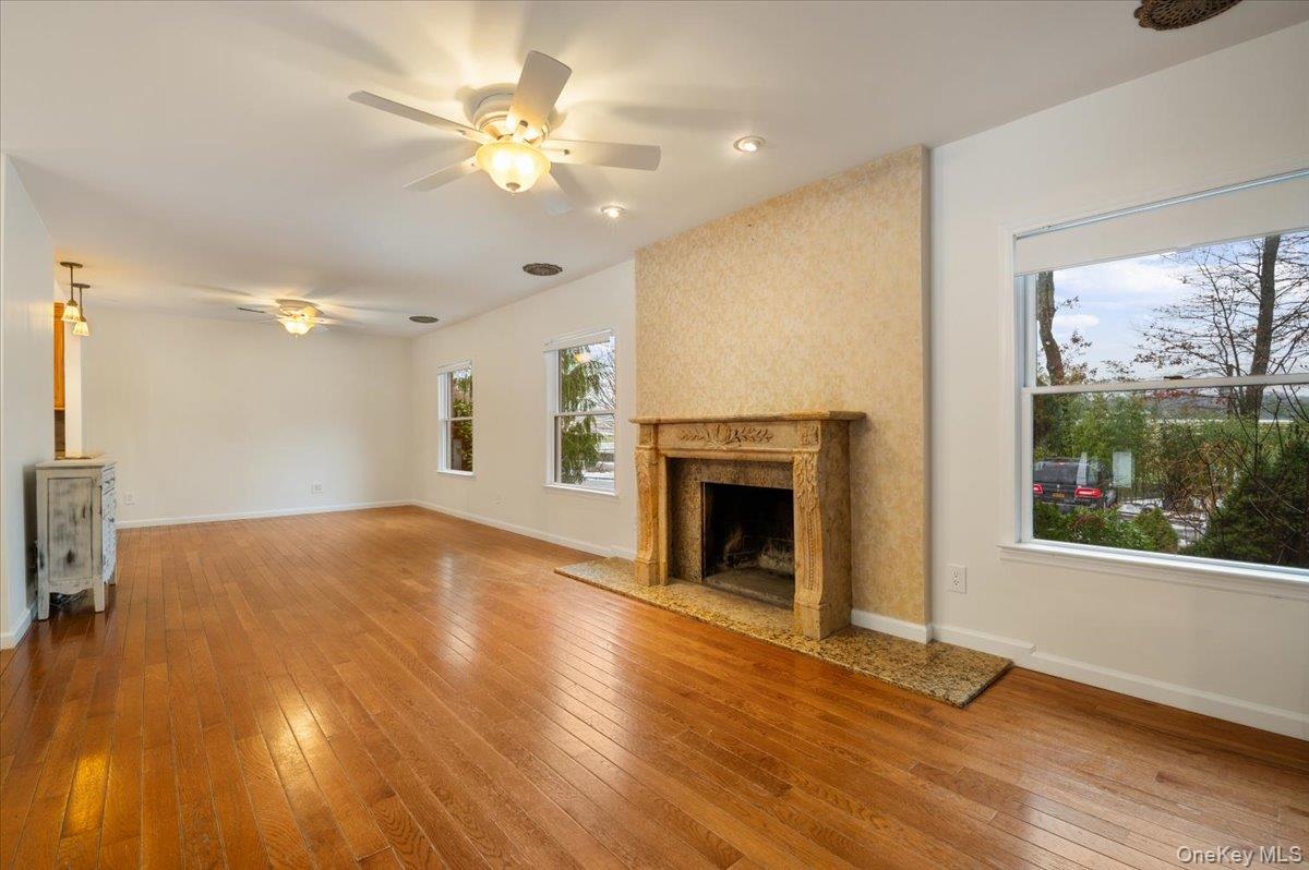 33 Fleets Cove Road Huntington, NY 11743 - Photo 15 of 44 an empty room with wooden floor a ceiling fan and a fireplace