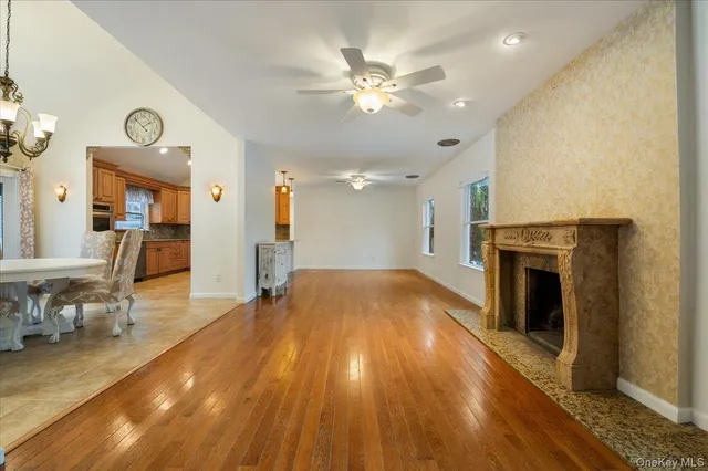 a view of a livingroom with a fireplace a ceiling fan and wooden floor