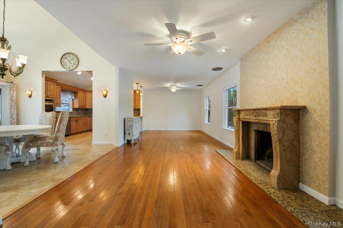 33 Fleets Cove Road Huntington, NY 11743 - Photo 9 of 44 a view of a livingroom with a fireplace a ceiling fan and wooden floor