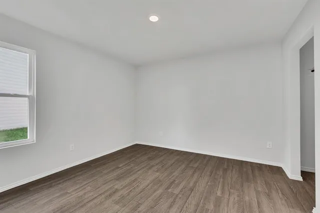 a view of an empty room and wooden floor and windows