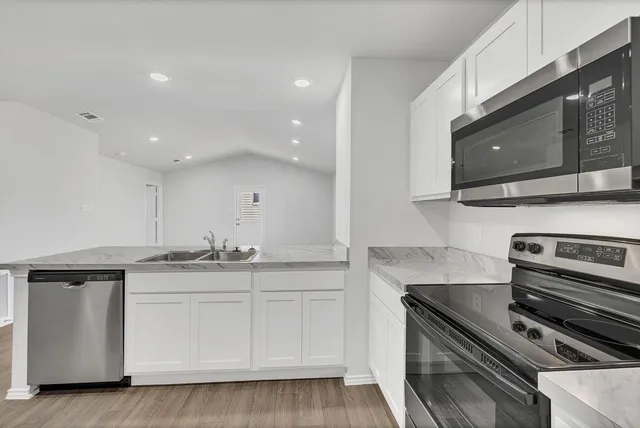 a kitchen with stainless steel appliances granite countertop a stove a microwave and a sink