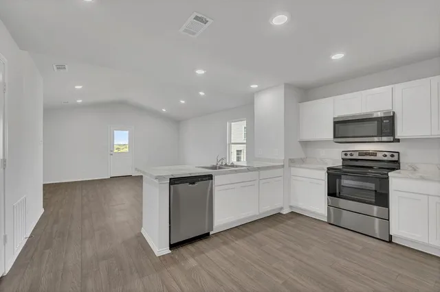 a kitchen with granite countertop a stove top oven and cabinets