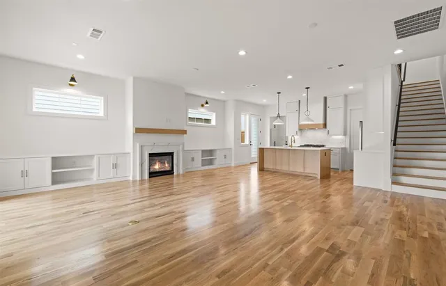 an empty room with wooden floor fireplace and windows