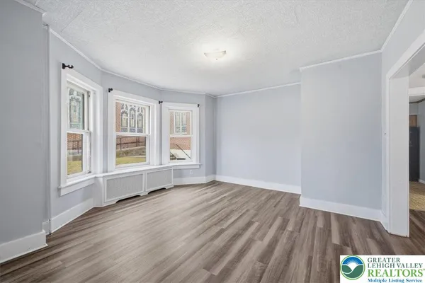 an empty room with wooden floor and windows