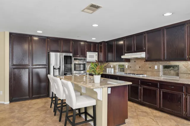 a kitchen with stainless steel appliances granite countertop a sink a stove and a refrigerator