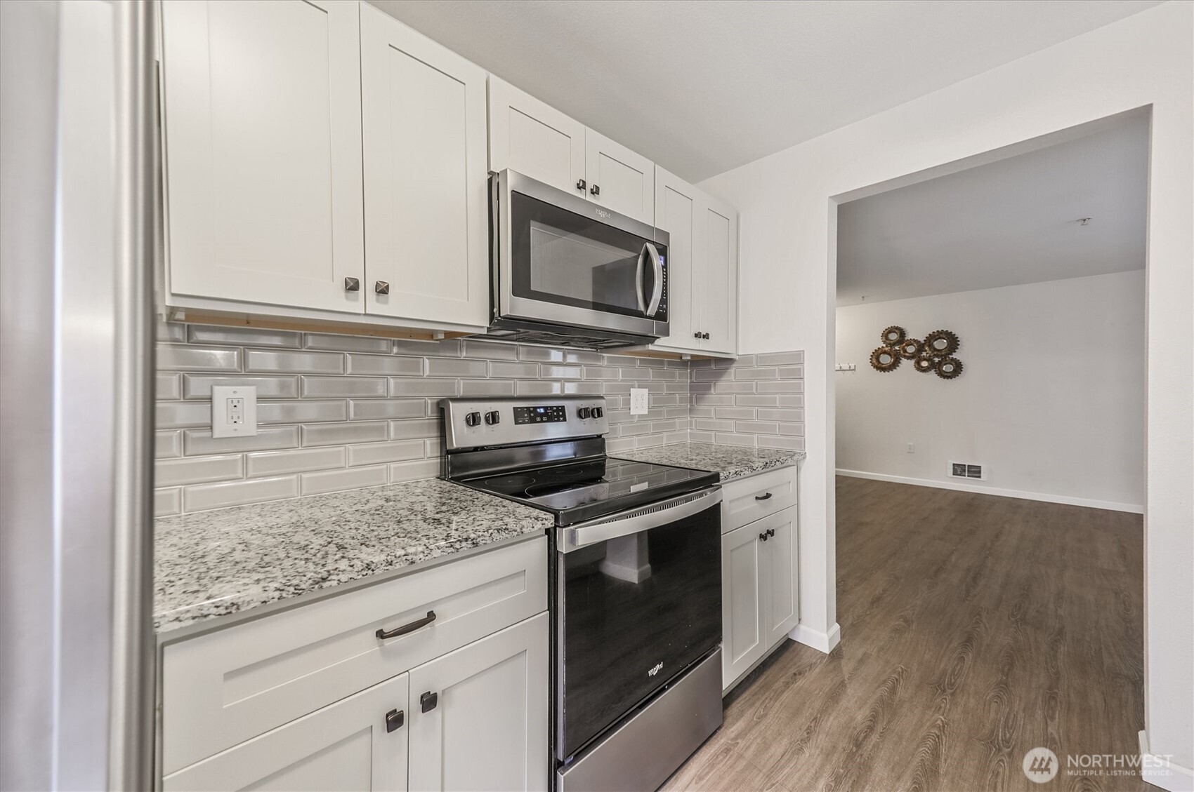 715 Harrington Place Southeast, Unit 2140 Renton, WA 98058 - Photo 15 of 36 a kitchen with granite countertop cabinets stainless steel appliances and wooden floor