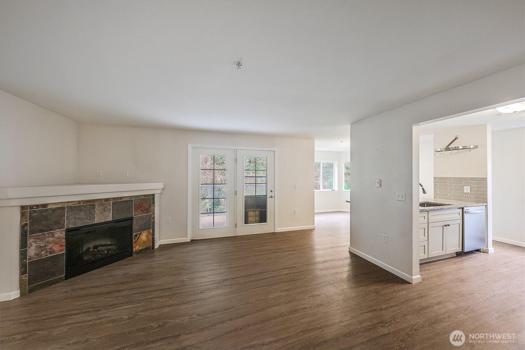 715 Harrington Place Southeast, Unit 2140 Renton, WA 98058 - Photo 4 of 36 an empty room with wooden floor fireplace and windows