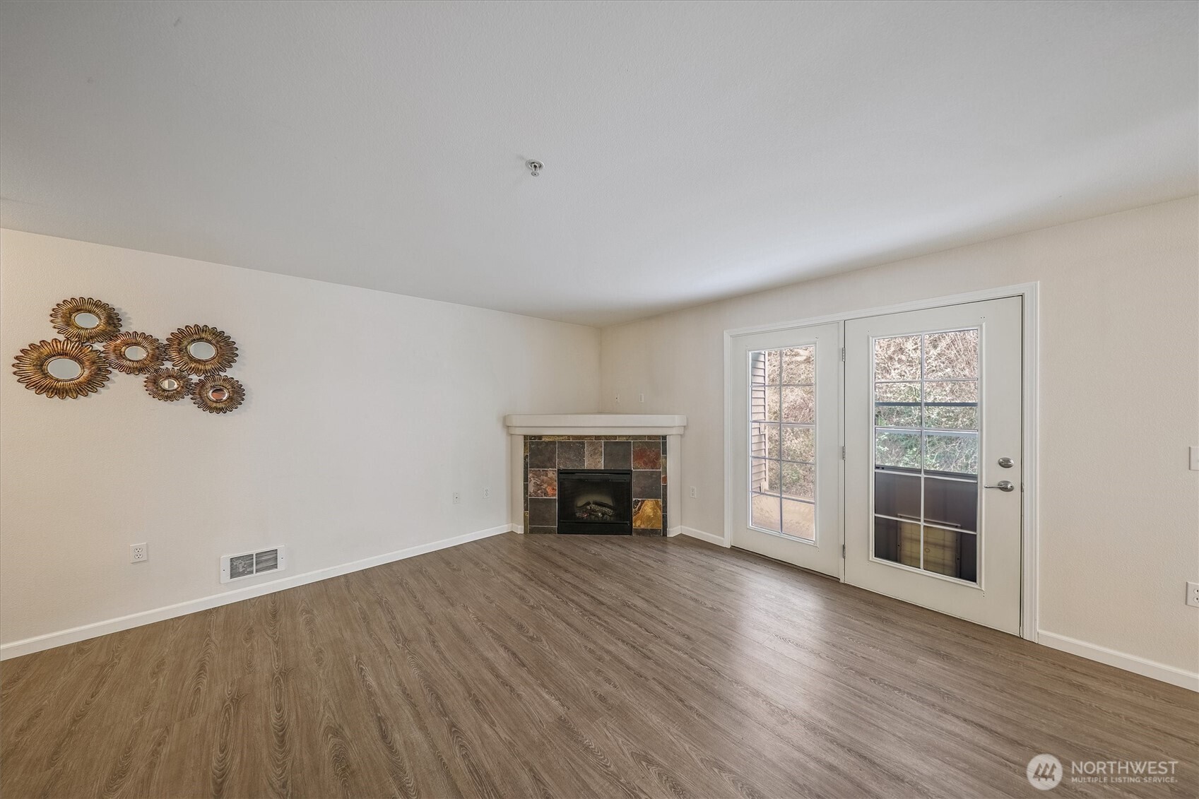 715 Harrington Place Southeast, Unit 2140 Renton, WA 98058 - Photo 5 of 36 an empty room with a fireplace and wooden floor