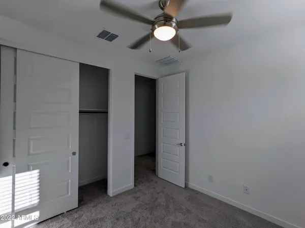 an empty room with ceiling fan and window