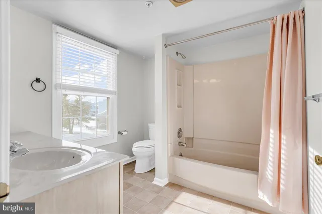 a bathroom with a granite countertop bathtub shower sink vanity and toilet