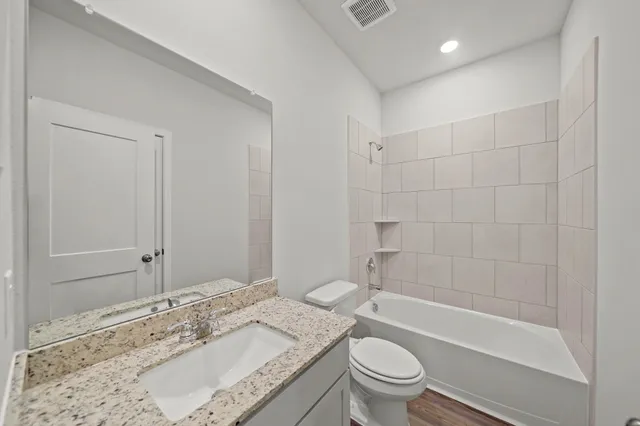 a bathroom with a granite countertop sink a toilet and shower