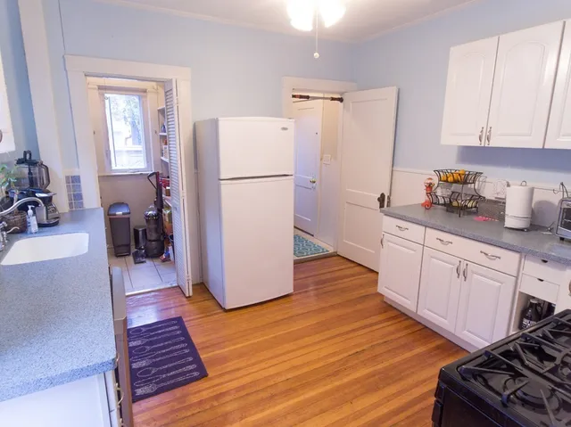a kitchen with sink a refrigerator and white cabinets