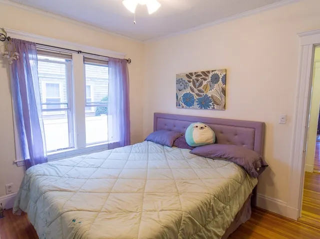 a large bed sitting in a bedroom next to a window and a chandelier