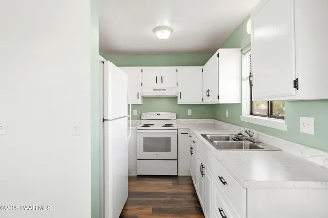 a kitchen with granite countertop a sink stainless steel appliances and white cabinets