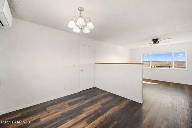 an empty room with wooden floor ceiling fan and windows