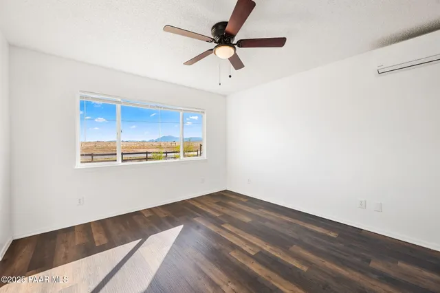 a view of an empty room with window and wooden floor