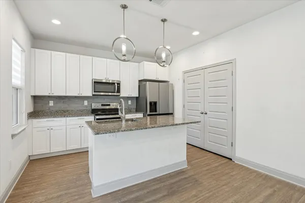 a kitchen with granite countertop a sink stainless steel appliances and white cabinets