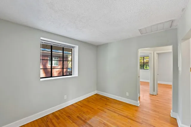 an empty room with wooden floor and windows