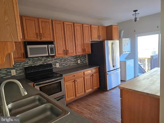 a kitchen with granite countertop wooden cabinets a refrigerator a stove a sink and dishwasher with wooden floor