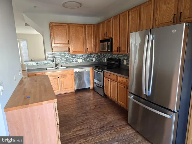 a kitchen with granite countertop a refrigerator stove top oven and sink