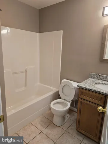 a bathroom with a granite countertop toilet and a bathtub