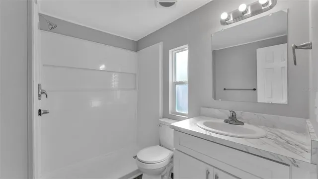 a bathroom with a granite countertop sink a toilet and a mirror