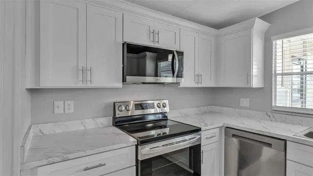 a kitchen with stainless steel appliances granite countertop white cabinets and a stove top oven