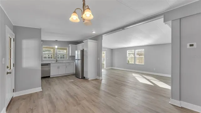 a view of a kitchen with a refrigerator a ceiling fan and wooden floor