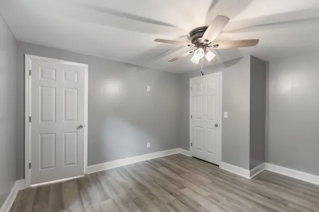 wooden floor in an empty room with a chandelier fan