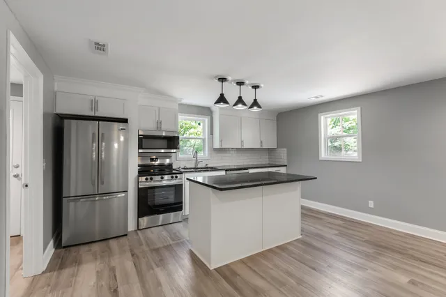 a kitchen with granite countertop a refrigerator and a stove top oven