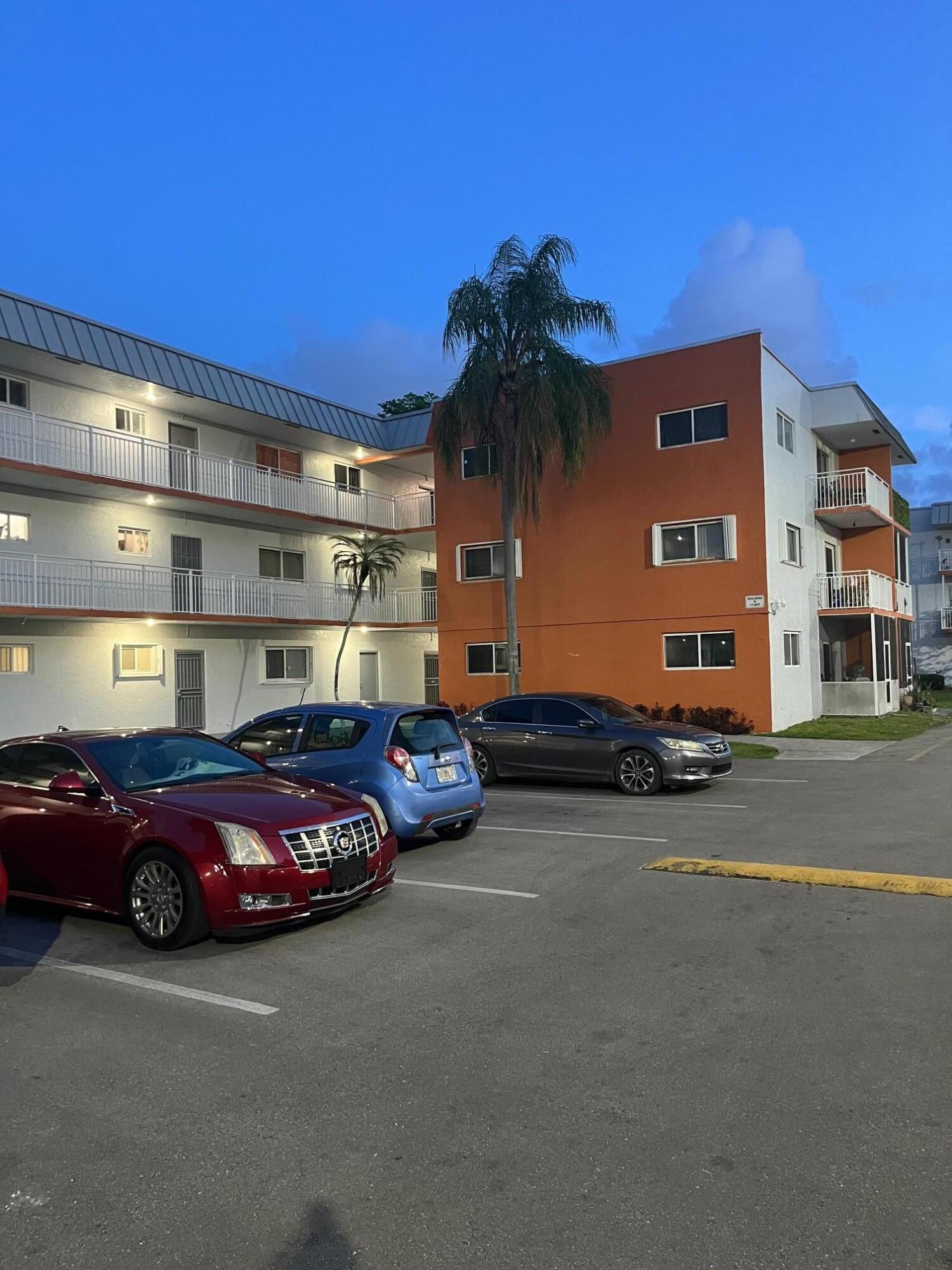 11307 Southwest 200th Street, Unit 313B Miami, FL 33157 - Photo 1 of 8 a front view of a building with cars parked