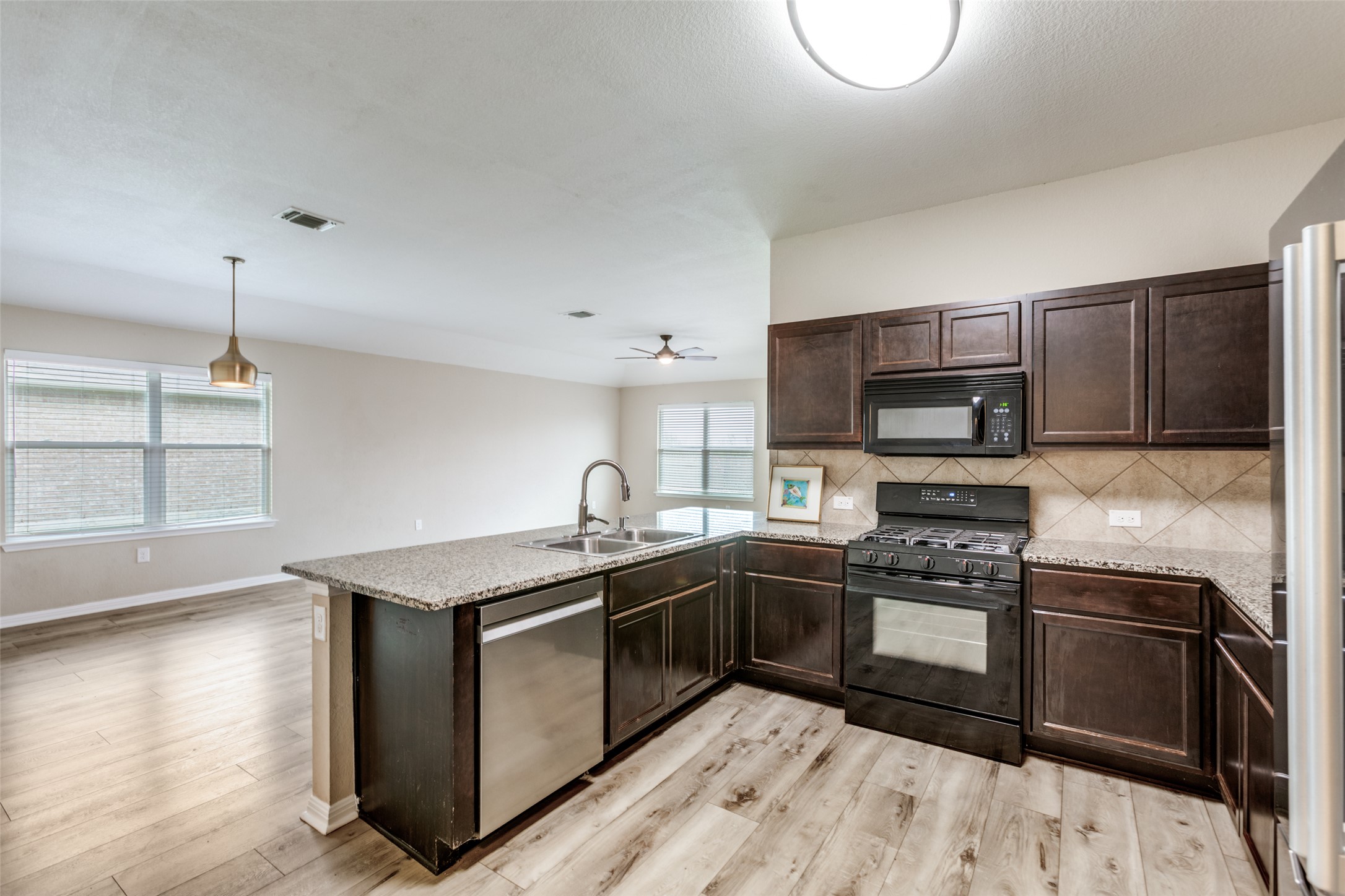 2909 Centrum Drive Austin, TX 78754 - Photo 17 of 30 The kitchen features dark wood cabinetry, granite countertops, and stainless steel appliances, including a dishwasher and gas range with an oven