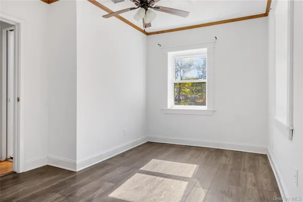 a view of an empty room with a window and wooden floor