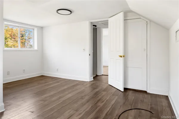 an empty room with wooden floor closet and windows
