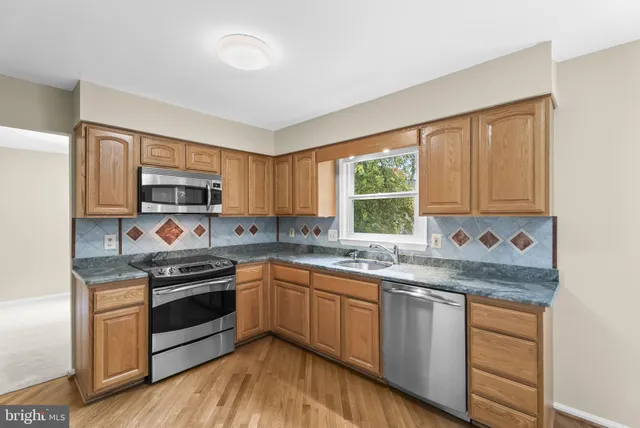 a kitchen with stainless steel appliances granite countertop wooden cabinets stove top oven and sink
