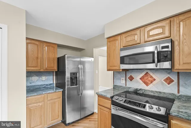 a kitchen with stainless steel appliances granite countertop a stove a microwave and a refrigerator