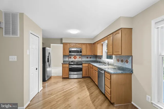 a kitchen with stainless steel appliances granite countertop a refrigerator a stove and a sink