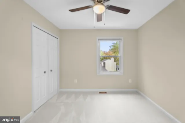 an empty room with a window and a fan