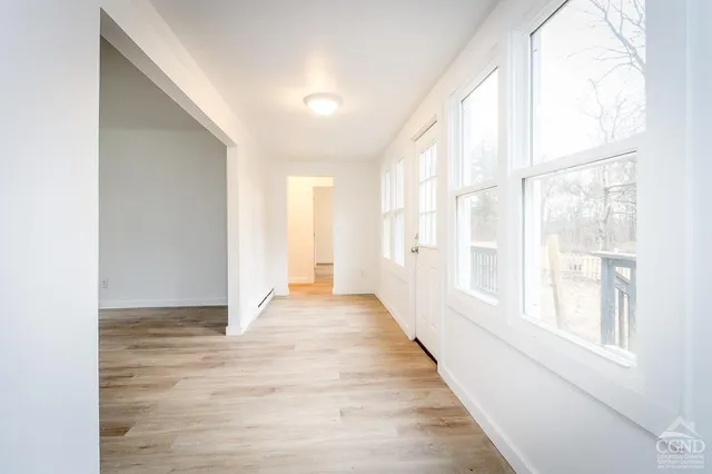 a view of an empty room with wooden floor and a window