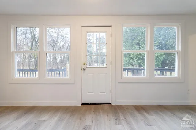 a view of an empty room with wooden floor and a window