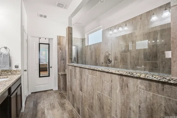 a bathroom with a granite countertop sink a mirror and a shower