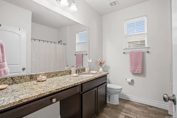 a bathroom with a granite countertop sink a toilet and a mirror