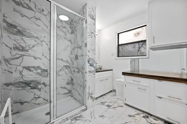 a bathroom with a granite countertop sink a mirror and shower