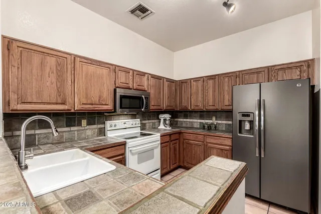 a kitchen with stainless steel appliances granite countertop a sink stove refrigerator and cabinets