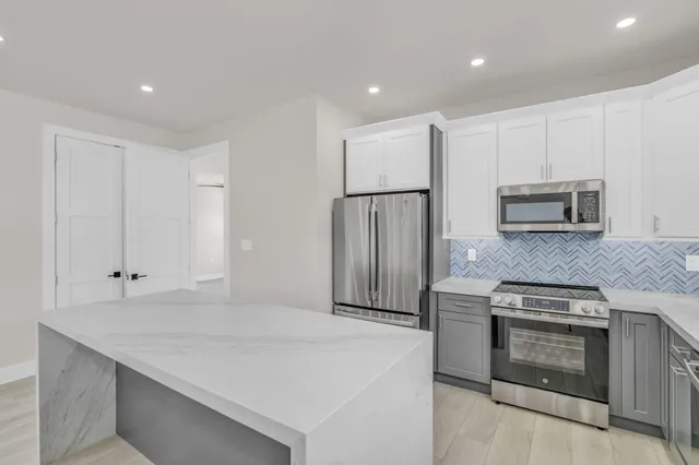 a kitchen with kitchen island a stove top oven and refrigerator